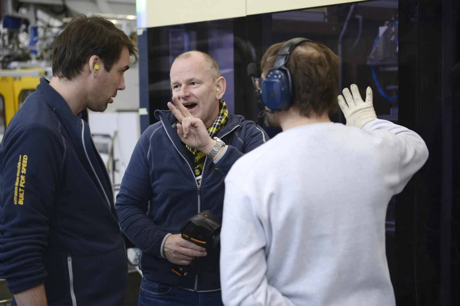 Andreas Lichtenauer discussing blow moulding technology with colleagues on the production floor